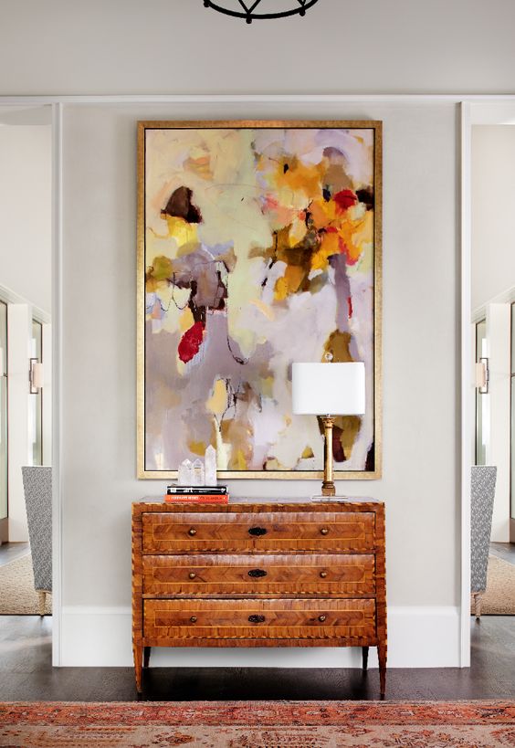 Oversized abstract yellow red and lavender artwork above a set of drawers in foyer