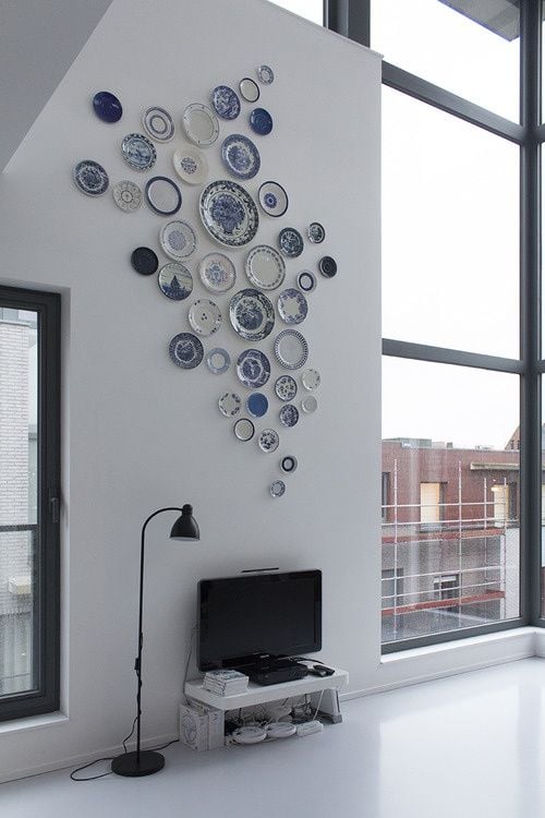 blue and white plates hanging on the wall of a modern loft above a tv