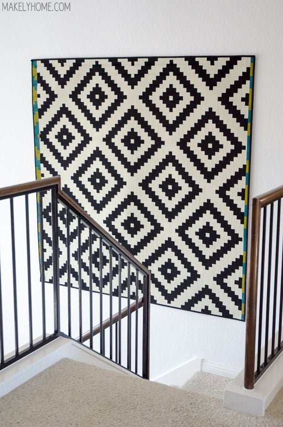 Black and white geometric wall hanging on the stairwell with white walls