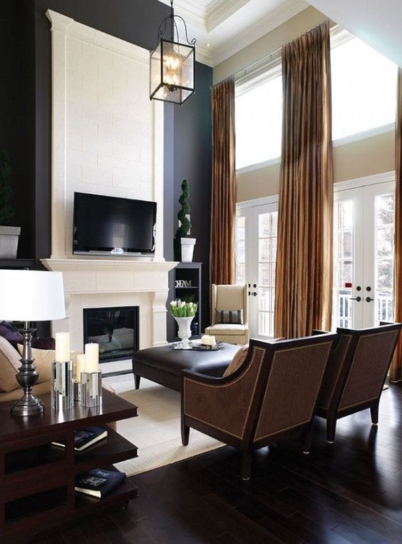 Living room with tall walls and white stone fireplace with TV above