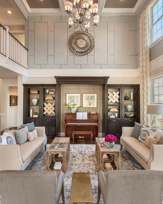 Two story living room with gray wall molding and sunburst mirror above built in with piano