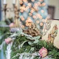 christmas cedar garland on mantel with dried pink roses and snowy branches added