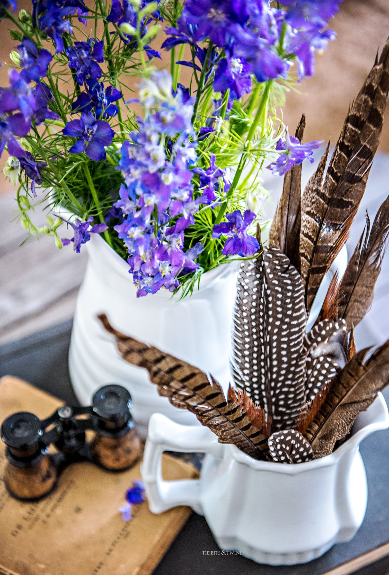 Spring vignette with purple flowers, ironstone and feathers