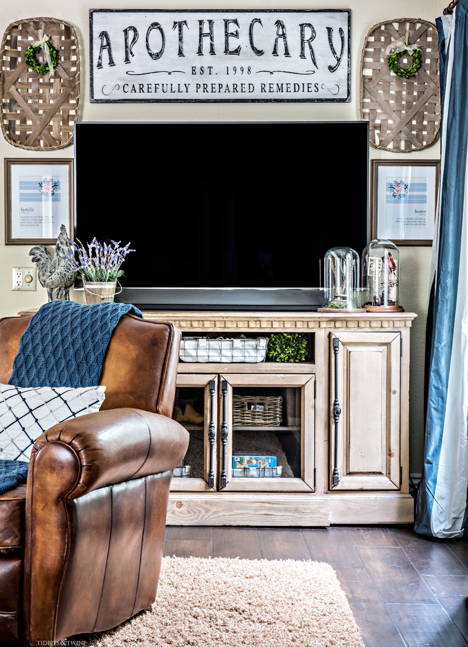 A French family room TV gallery wall with tobacco baskets blue silk curtains and a leather recliner