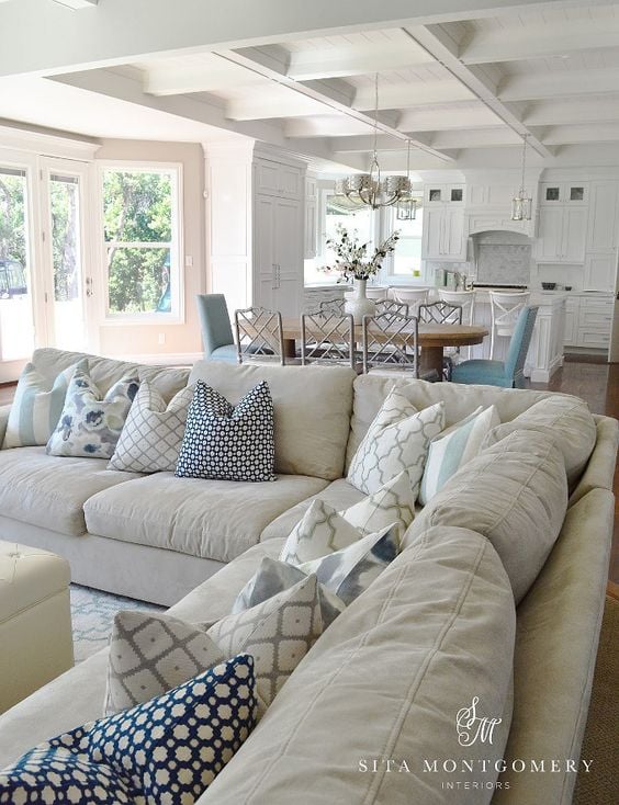 Large beige sectional in great room with white kitchen and blue accents