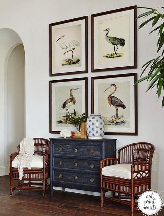 Entryway with bird pictures hanging above antique chest of drawers and chairs