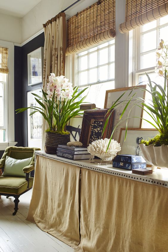 long table in front of window with seashells and orchids and artwork leaning