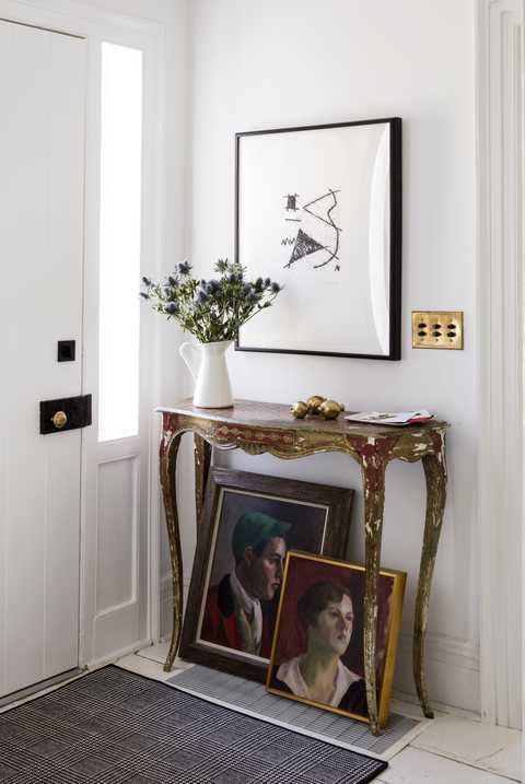 white entry with french console table and framed art leaning on the floor