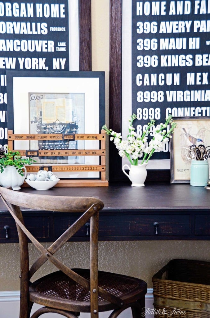 writing desk with layered artwork leaning on it and crossback chair