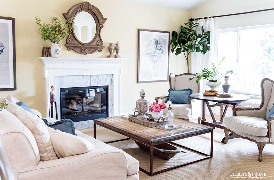 French inspired living room with wingback chairs, slipcovered sofa and mansard mirror above the mantel