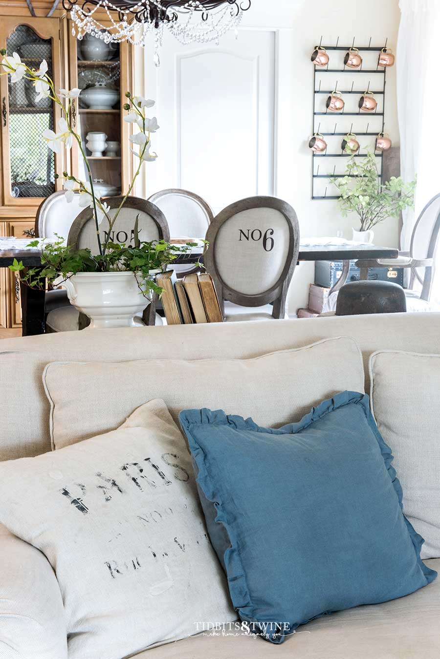 Grain sack pillows on a linen slipcovered sofa. Numbered dining chairs.