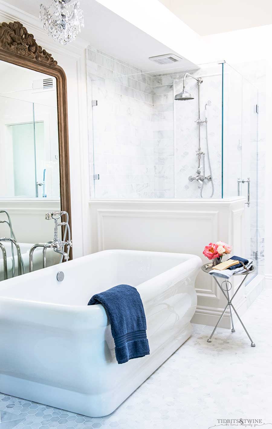 Elegant french master bathroom with freestanding tub next to shower with pony wall and white trim