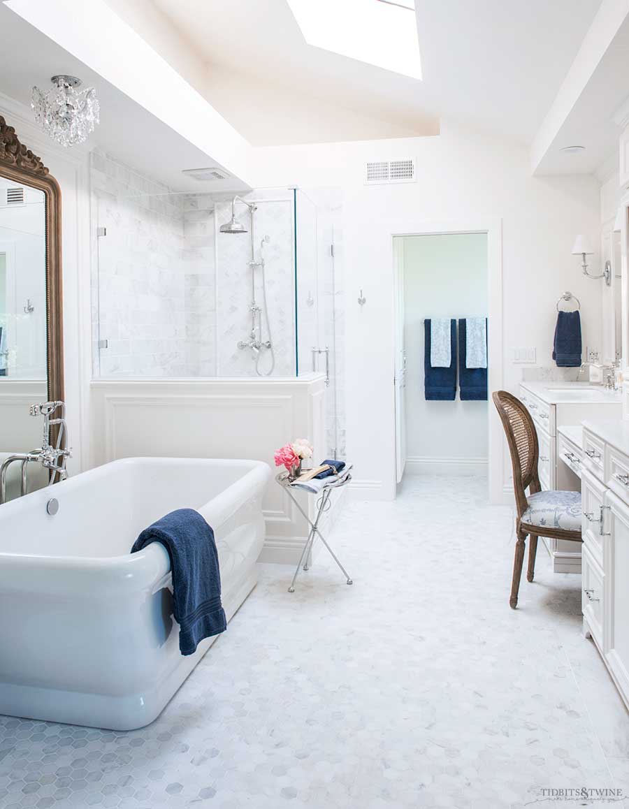 elegant marble bathroom with white hexagon marble floor white cabinets and shower pony wall