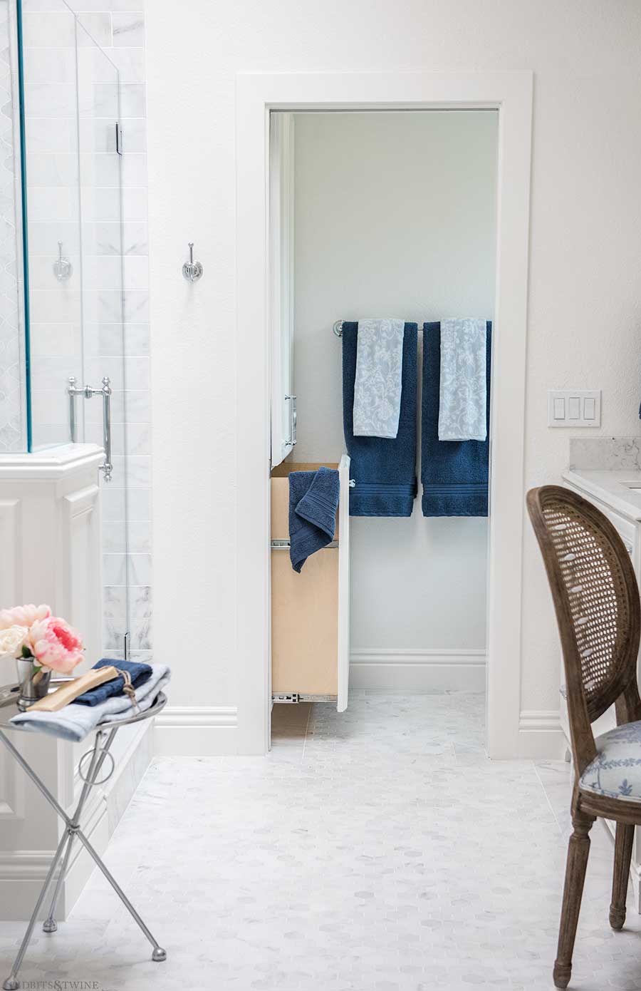 white marble bathroom built-in with pullout hamper in the water closet area