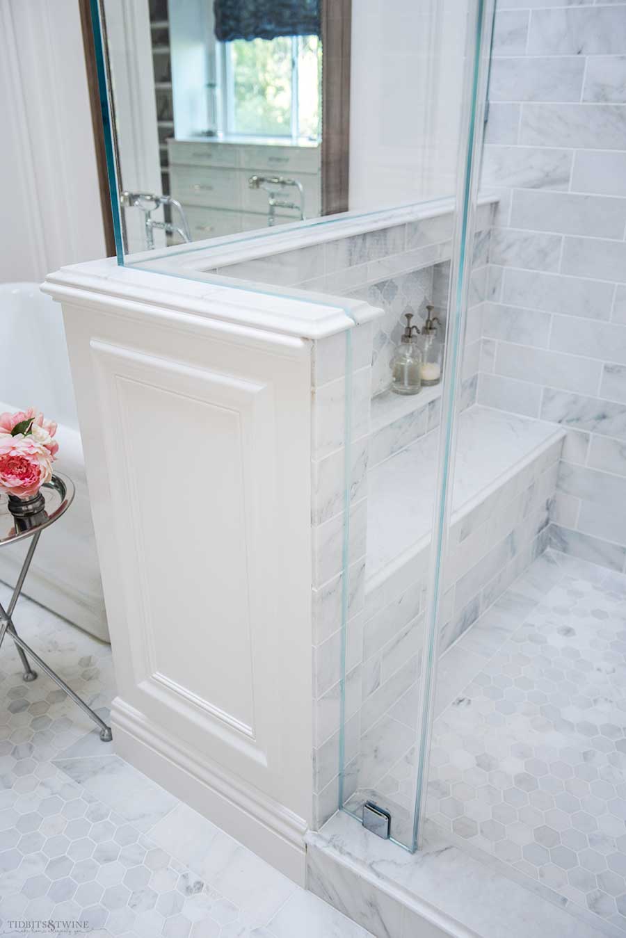 Shower pony wall with oversized carrara marble bench and shampoo niche