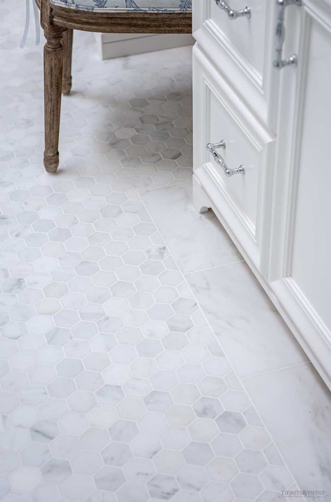 Venato Carrara marble hexagon floor with subway tile border in french elegant master bathroom next to custom white vanity cabinets