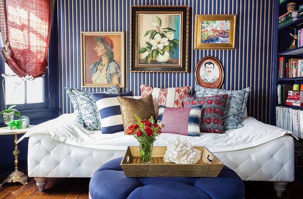 white tufted daybed with blue strip wallpaper and red blue pillows