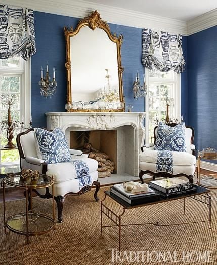 french living room with solid blue grasscloth wallpaper and gold mirror