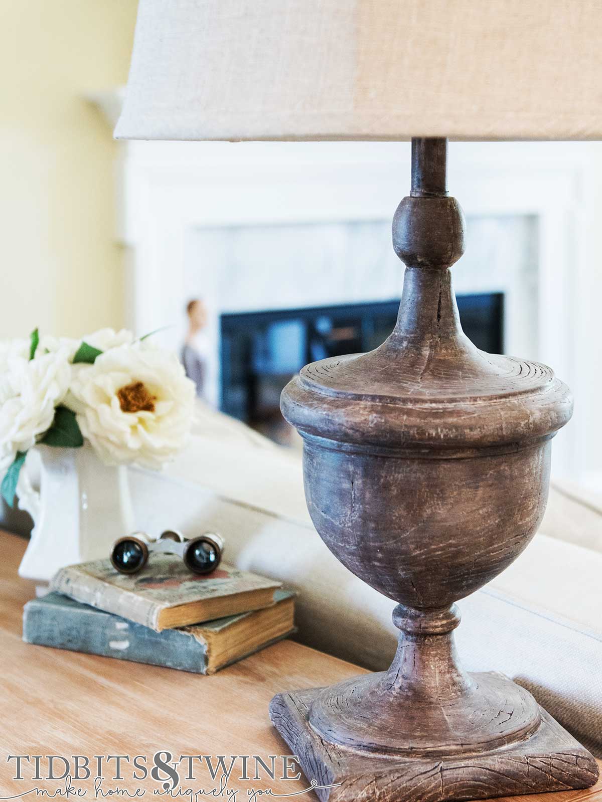 Closeup of lamp painted to look like aged wood sitting on console table behind couch in living room