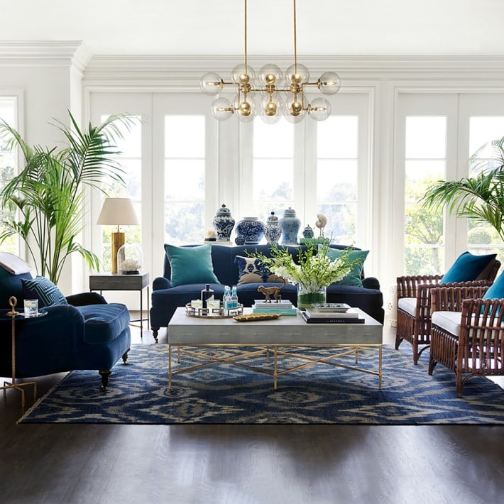 Blue velvet sofa and chair with white and gold coffee table and ikat rug