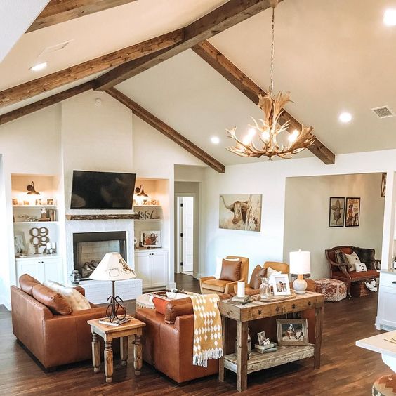 A Western style family room with leather sofas and rustic wood and antler light fixture