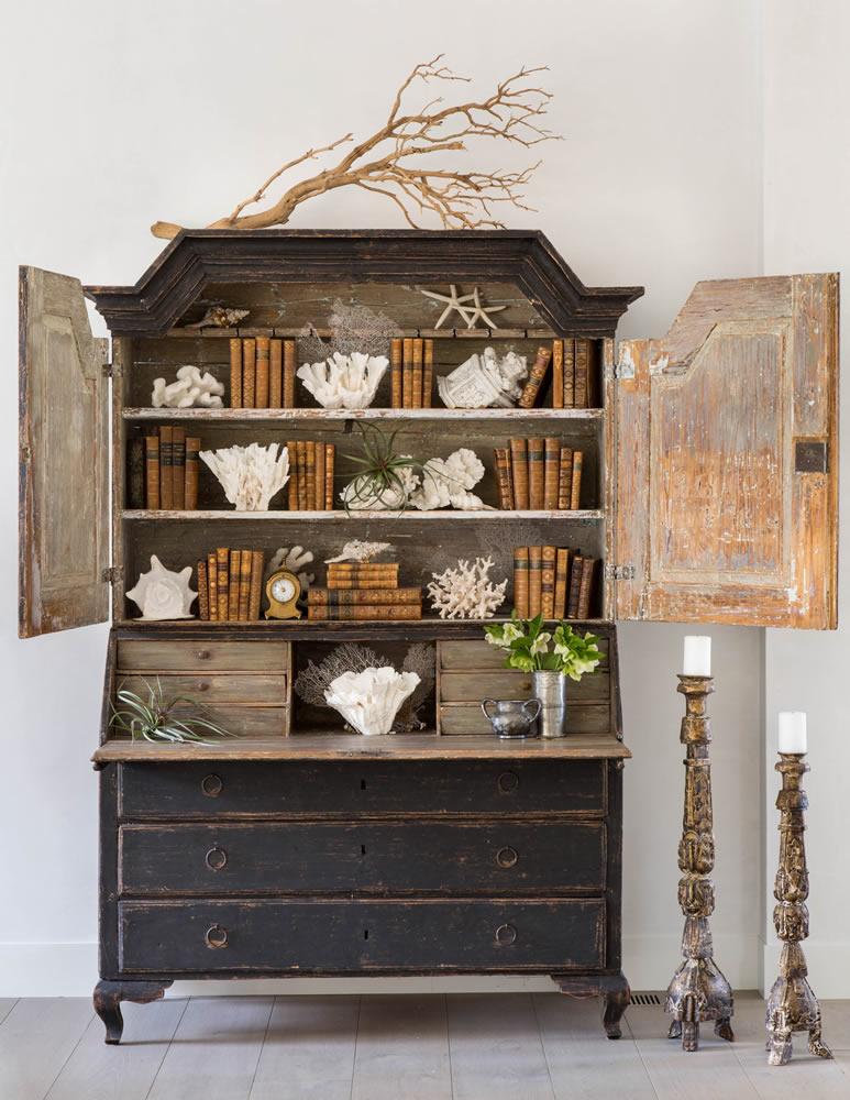 Brooke Giannetti black antique cabinet with books and two large candlesticks