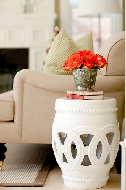 White garden stool used as a side table next to a beige sofa