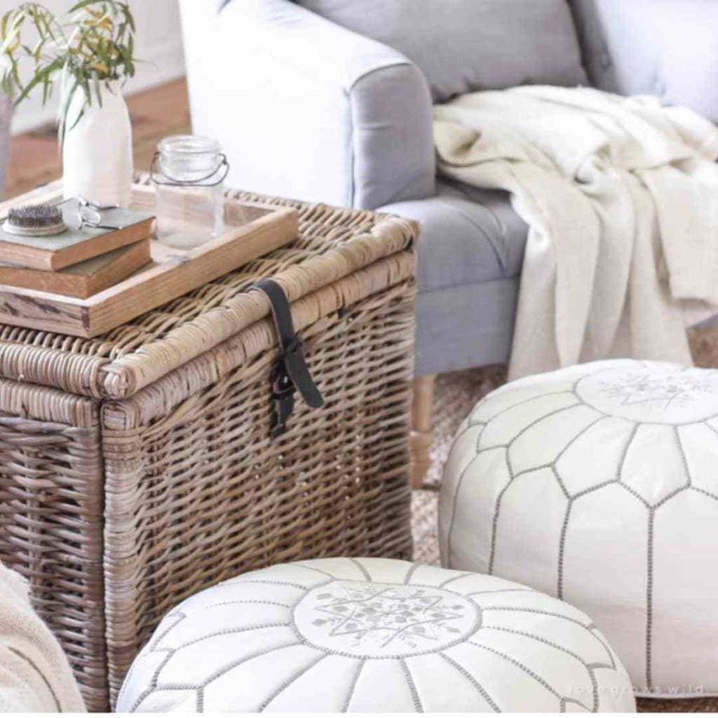 Lidded basket trunk with leather strap used as a side table between chair and Moroccan poufs