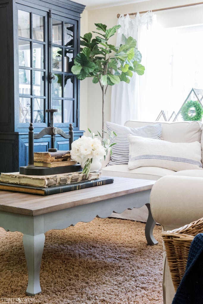 French country coffee table in family room with black cabinet and fiddle leaf fig