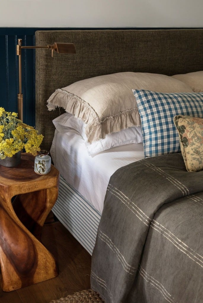 sculptural tree stump used as a side table next to a bed