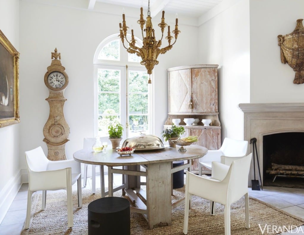 gustavian eating area with wood table and white chairs white walls and mora clock in corner