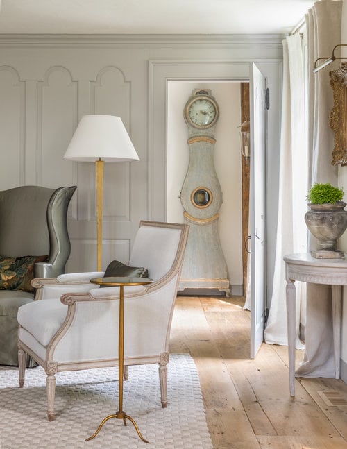 gustavian living room with mora clock showing through open door in hall