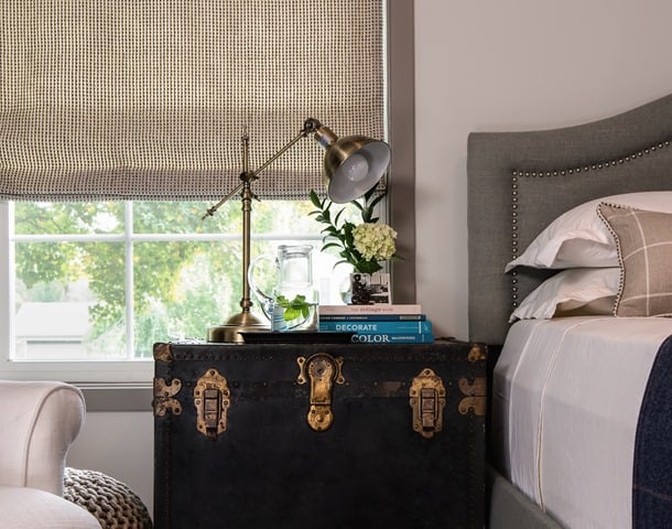 Vintage black trunk as a nightstand with a gold lamp on top