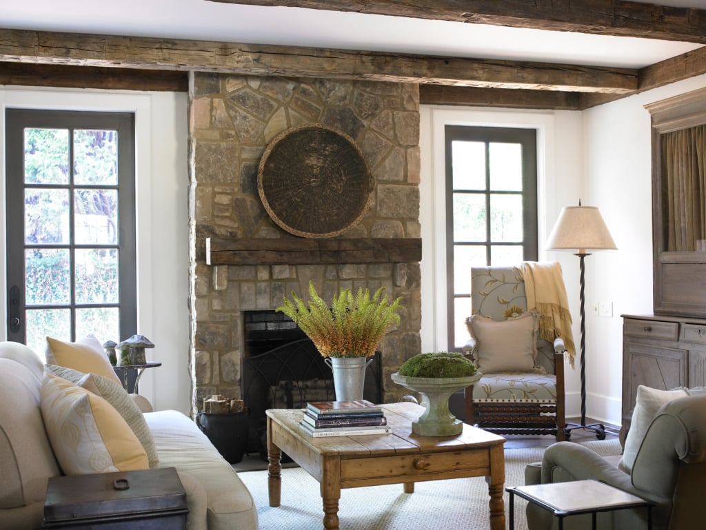 Den with stone fireplace flanked by french doors and beam ceiling