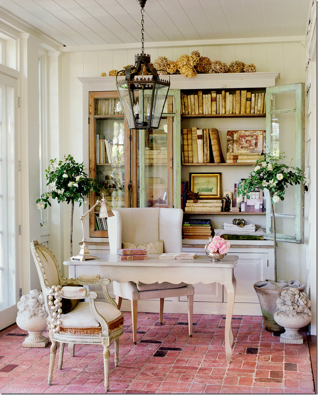 French home office with large bookcase filled with antique books and brick floor