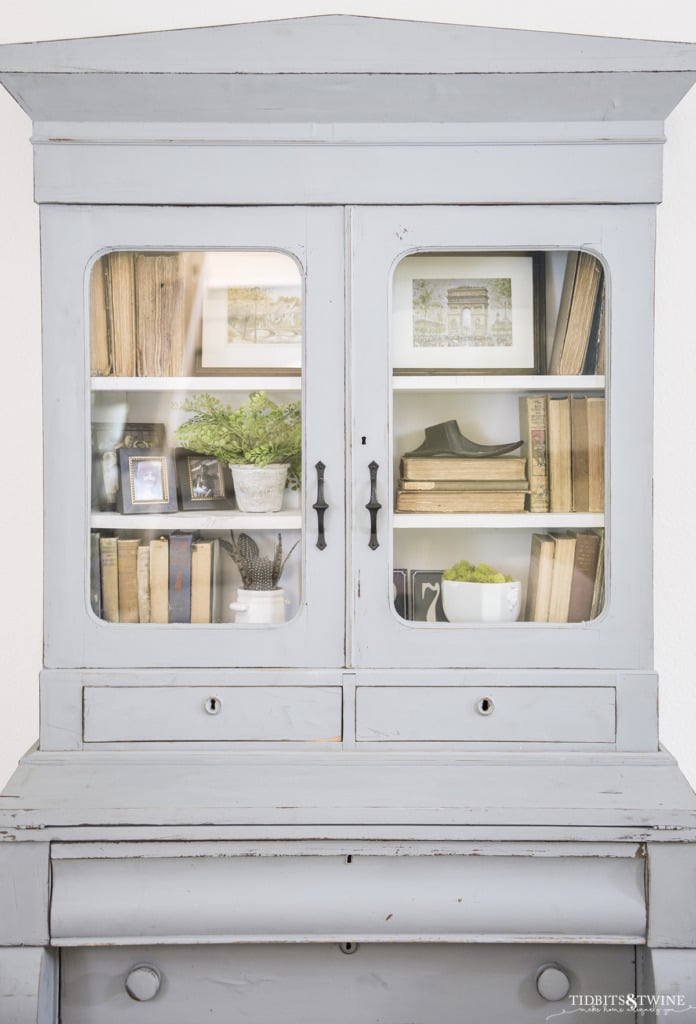 Blue french hutch with shelves styled with antique books and art