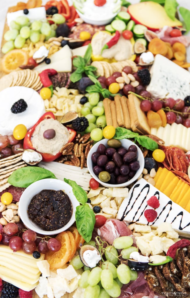 Closeup of charcuterie board showing fig spread olives cheeses and basil garnish