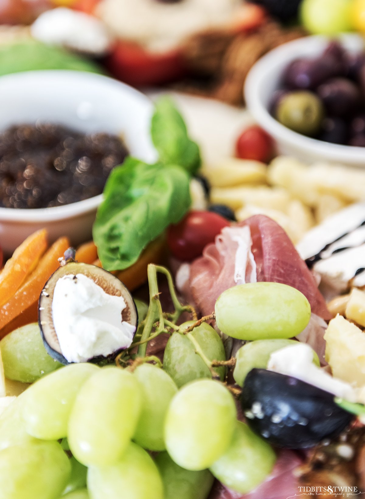 Closeup of large charcuterie board showing grapes and figs with goat cheese on top