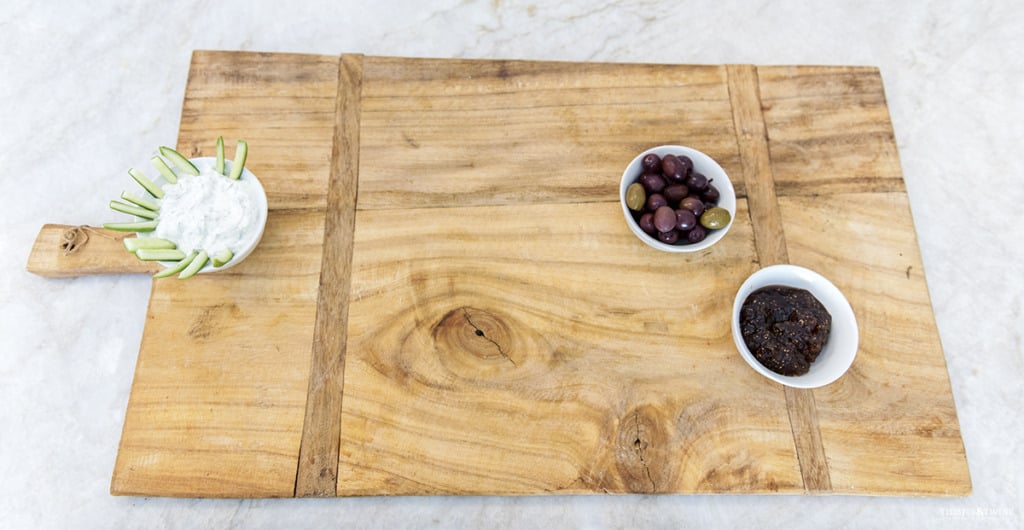 Antique Hungarian bread board on granite kitchen counter with three bowls of dips