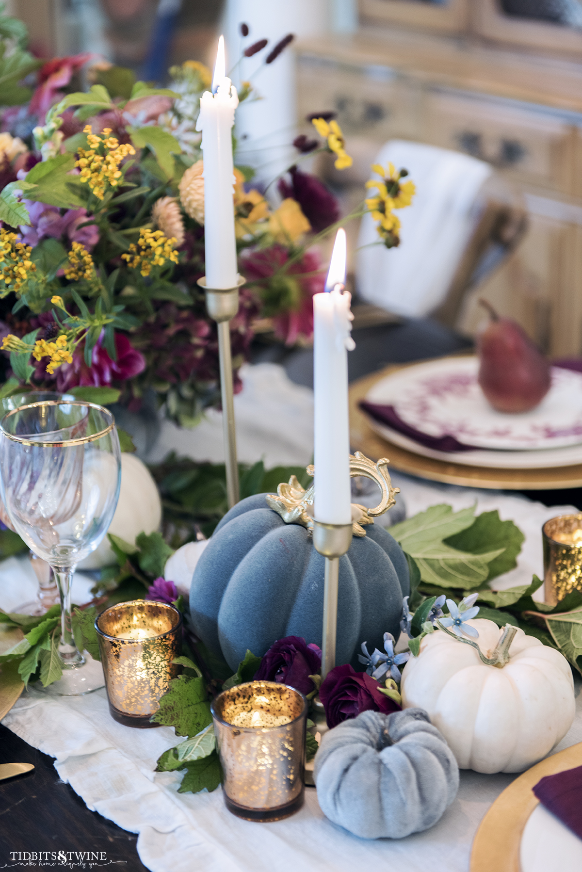 Closeup of elegant fall dining table with blue and white pumpkins gold accents and purple flowers