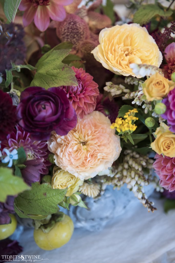 closeup of pink dahlias and yellow roses in blue antique french jardinere