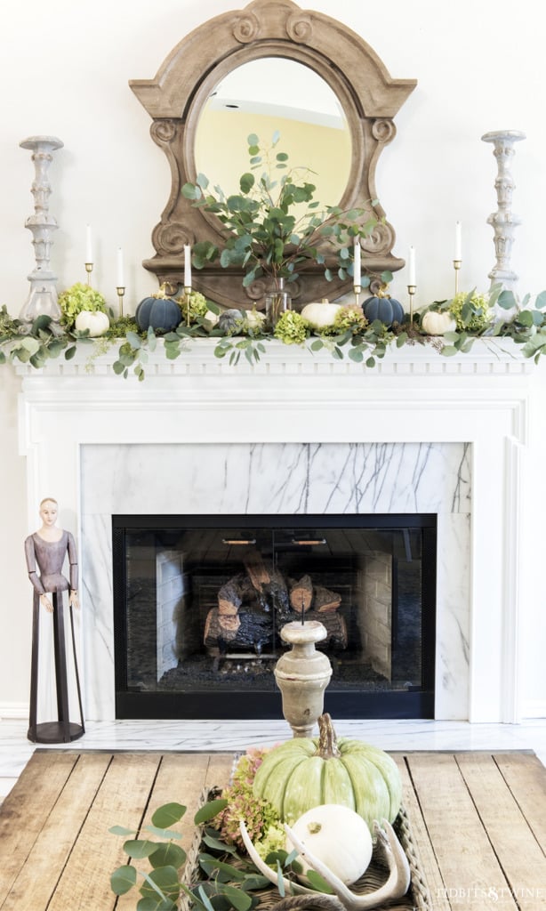 Living room fireplace decorated for fall with mansard mirror above and eucalyptus on mantel