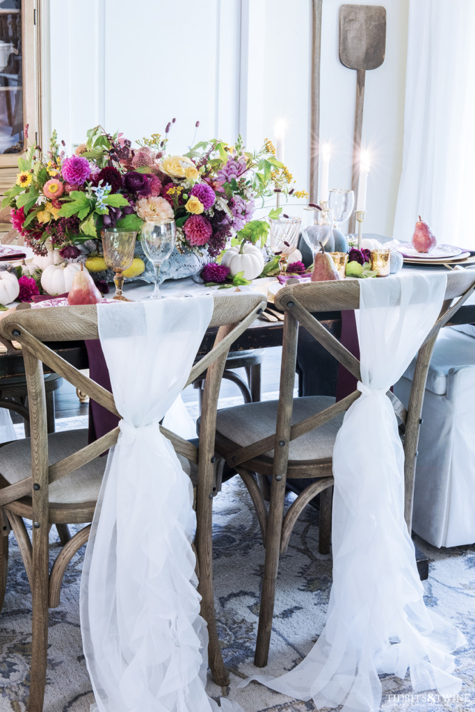 fall french dining room with white chairs and oversized colorful flowers and pumpkins on the table