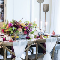 french dining room with brown cross back chairs and pink purple yellow and green flower arrangement in center