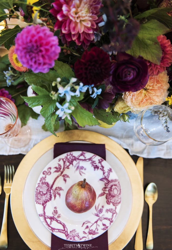 top down shot of fall place setting with burgundy plate and gold charge with pear on top