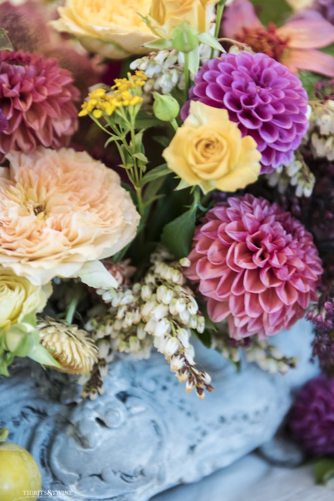 closeup of pink dahlias and yellow roses in blue antique french jardinere