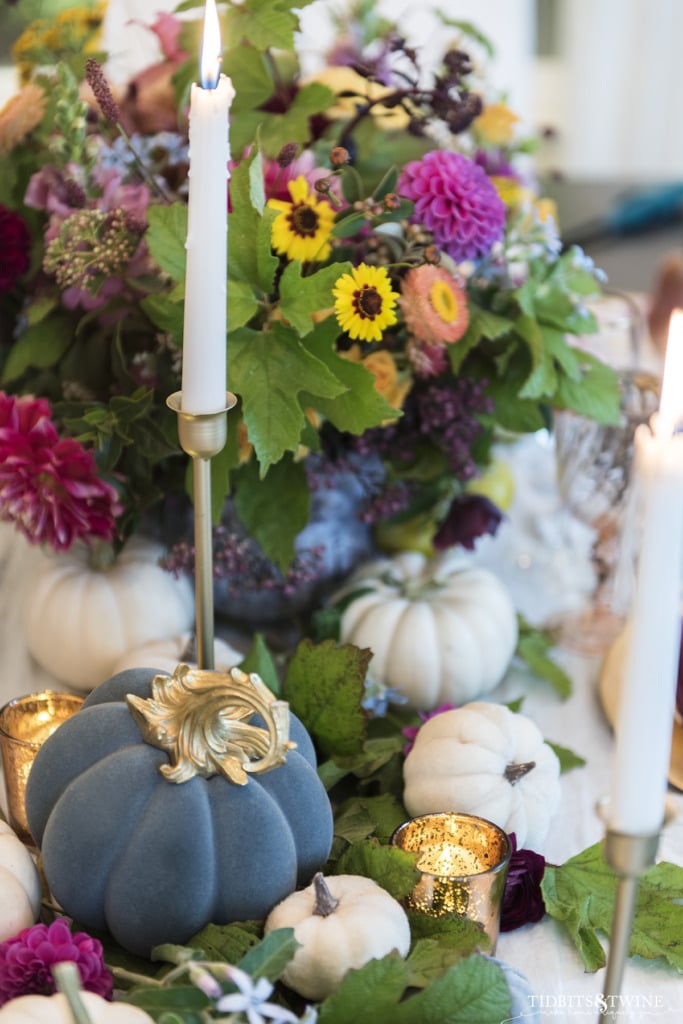 blue velvet pumpkin with gold stem with white candles in gold candlesticks and fall flowers