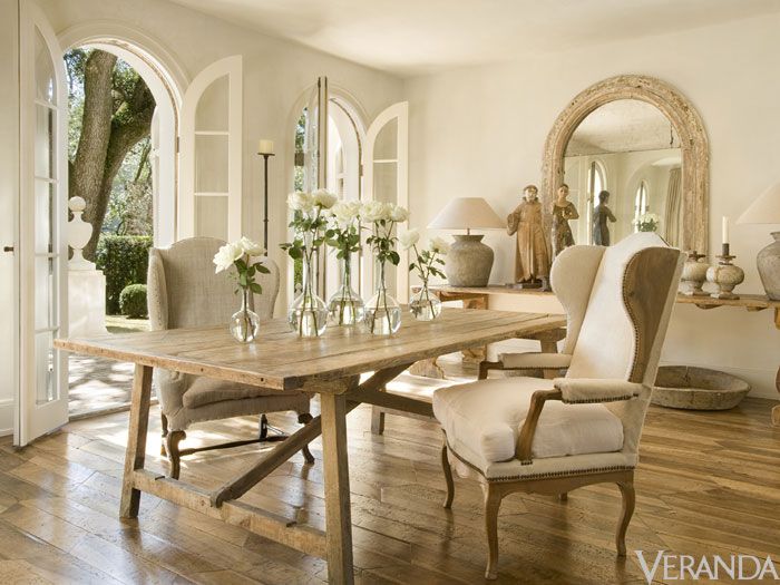 Neautral French dining room with wooden floors and two wingback chairs at table