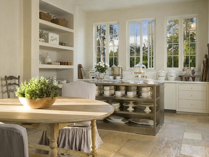 White kitchen with open shelving and round french table with slipcovered chairs