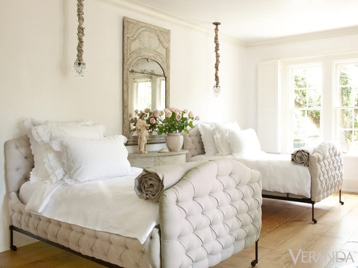 White bedroom with two twin white tufted beds and french mirror between